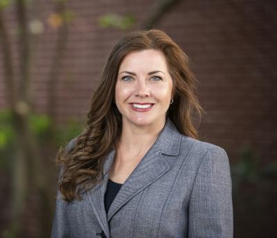 Woman smiling, posing for picture in grey blazer.